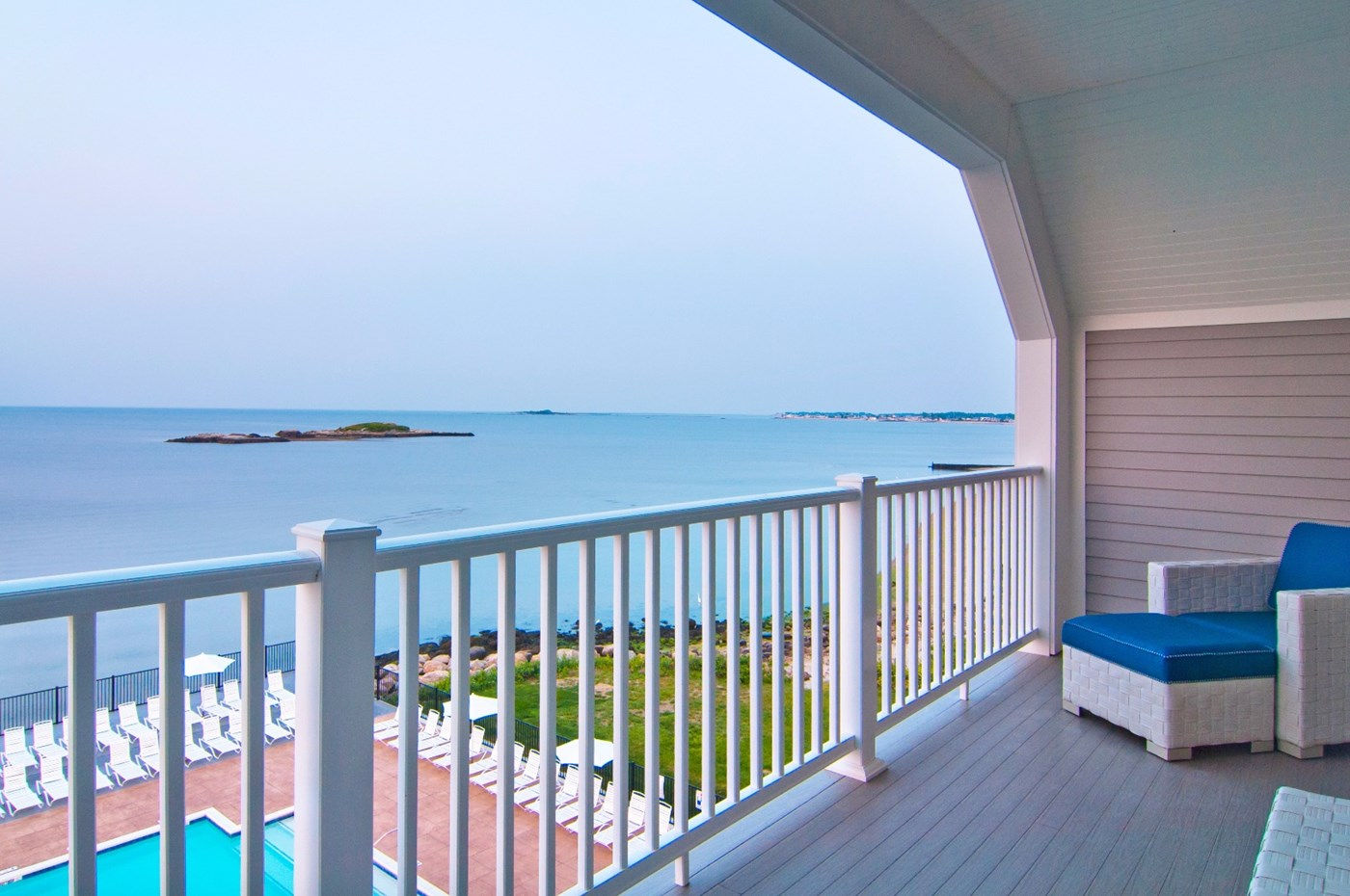 a deck with a chair and a pool overlooking the water