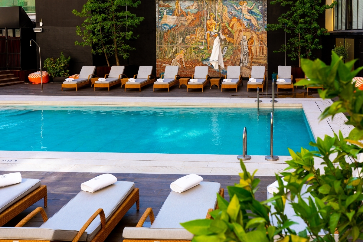 a pool with lounge chairs and a mural on the wall