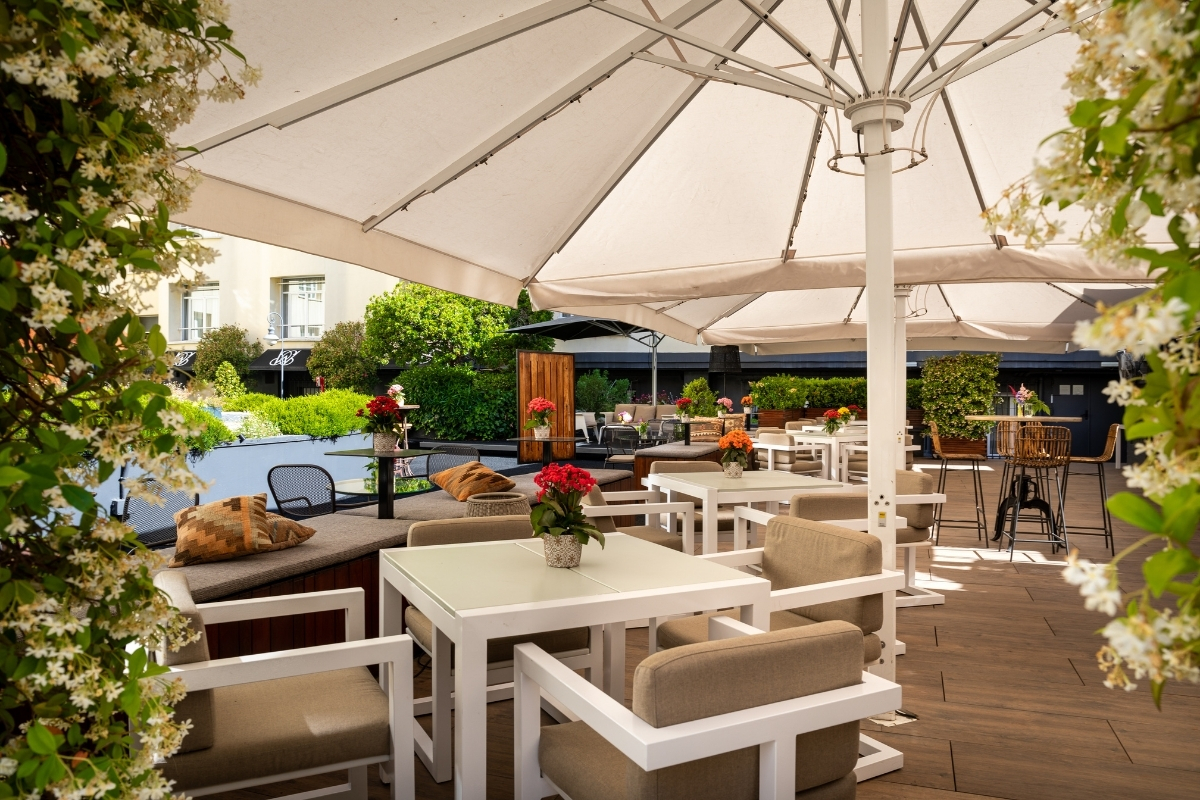a patio with tables and chairs and a large umbrella