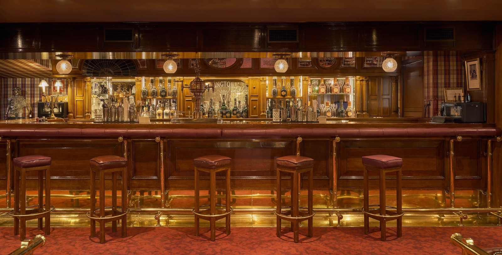 a bar with a row of stools and a row of bottles