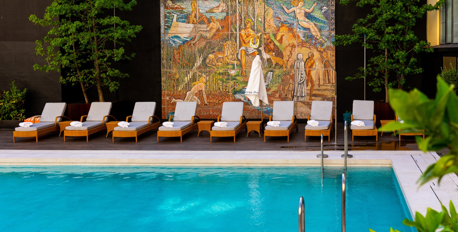 a pool with chairs and a mosaic wall