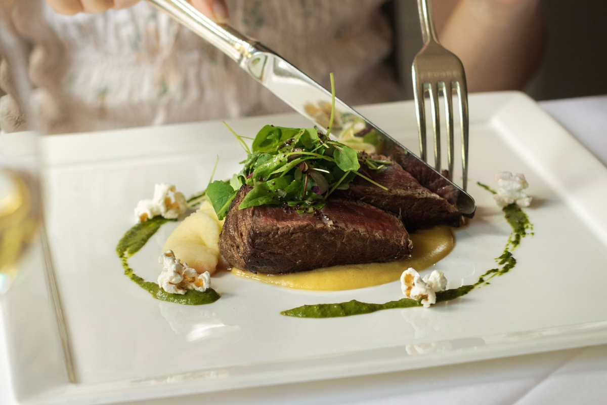 a fork and knife cutting a piece of meat
