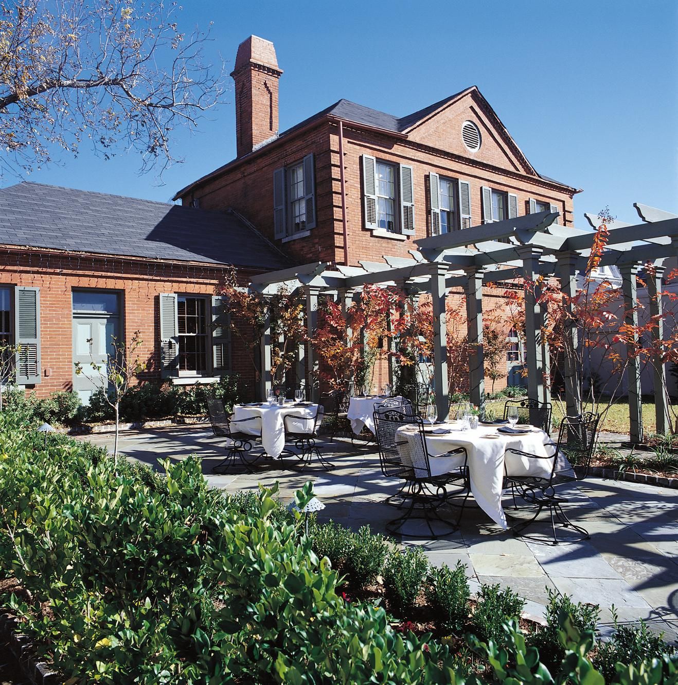 a patio with tables and chairs in front of a brick building