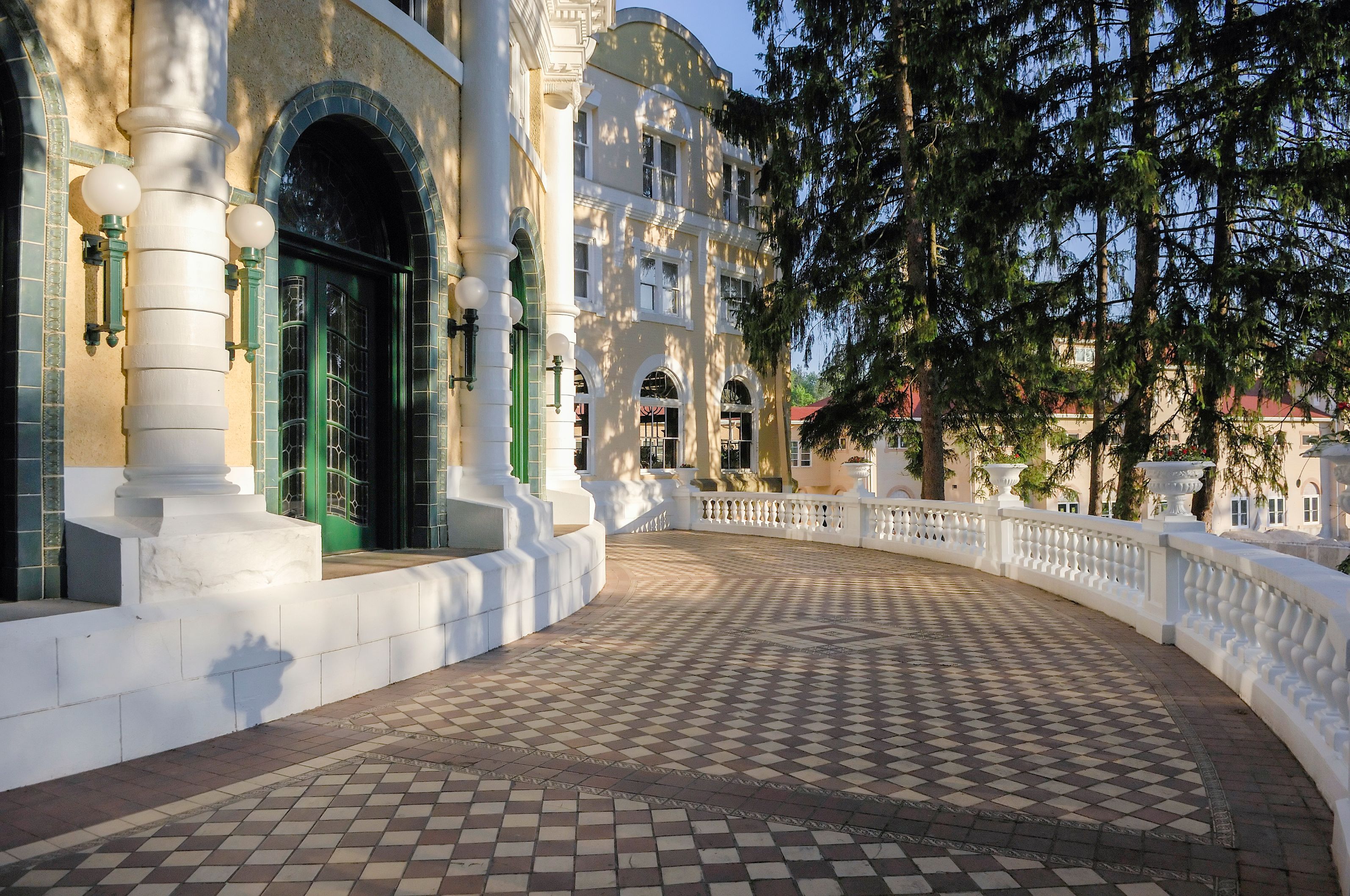 a walkway with a white railing and a building with trees