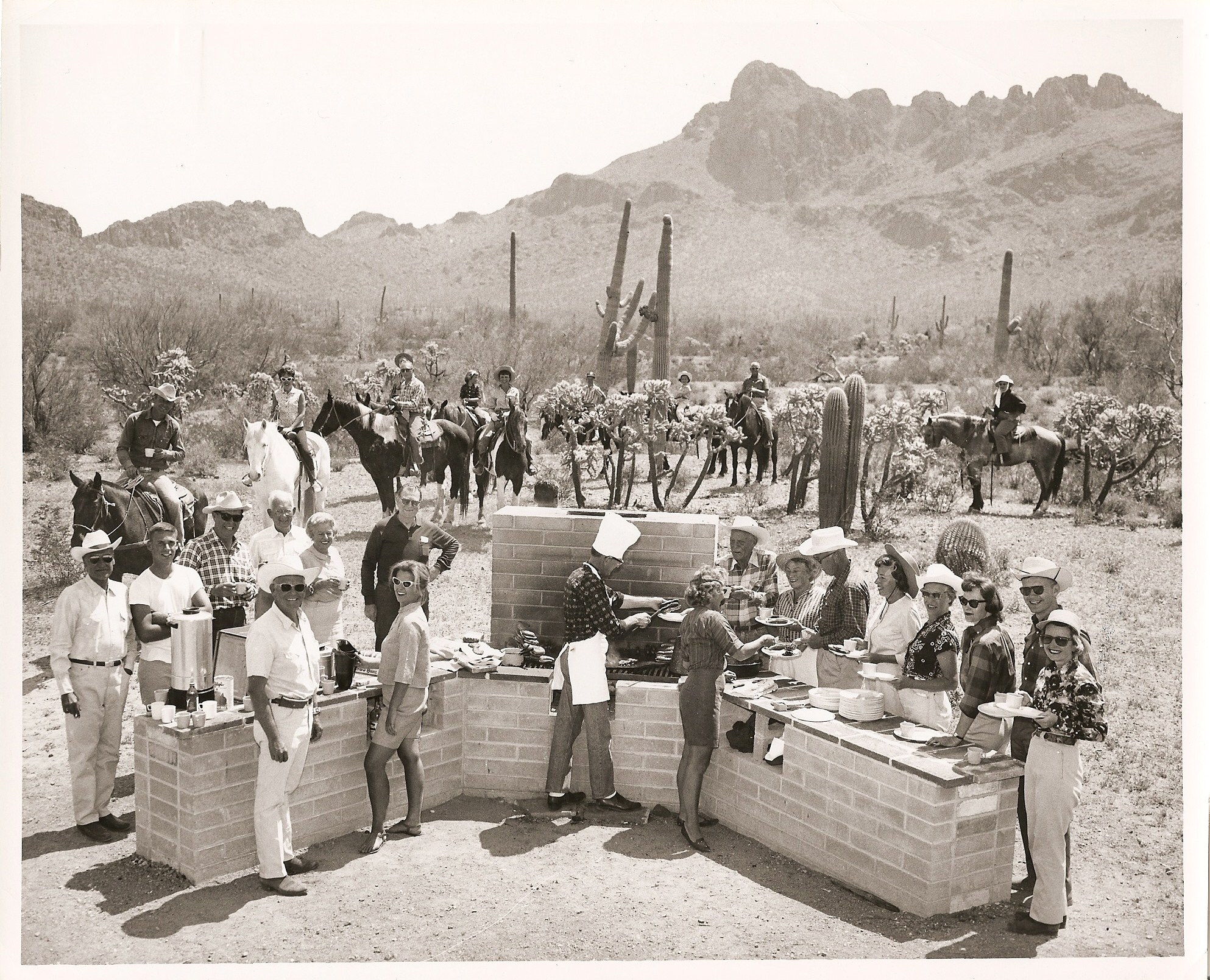 a group of people standing around a brick barbecue