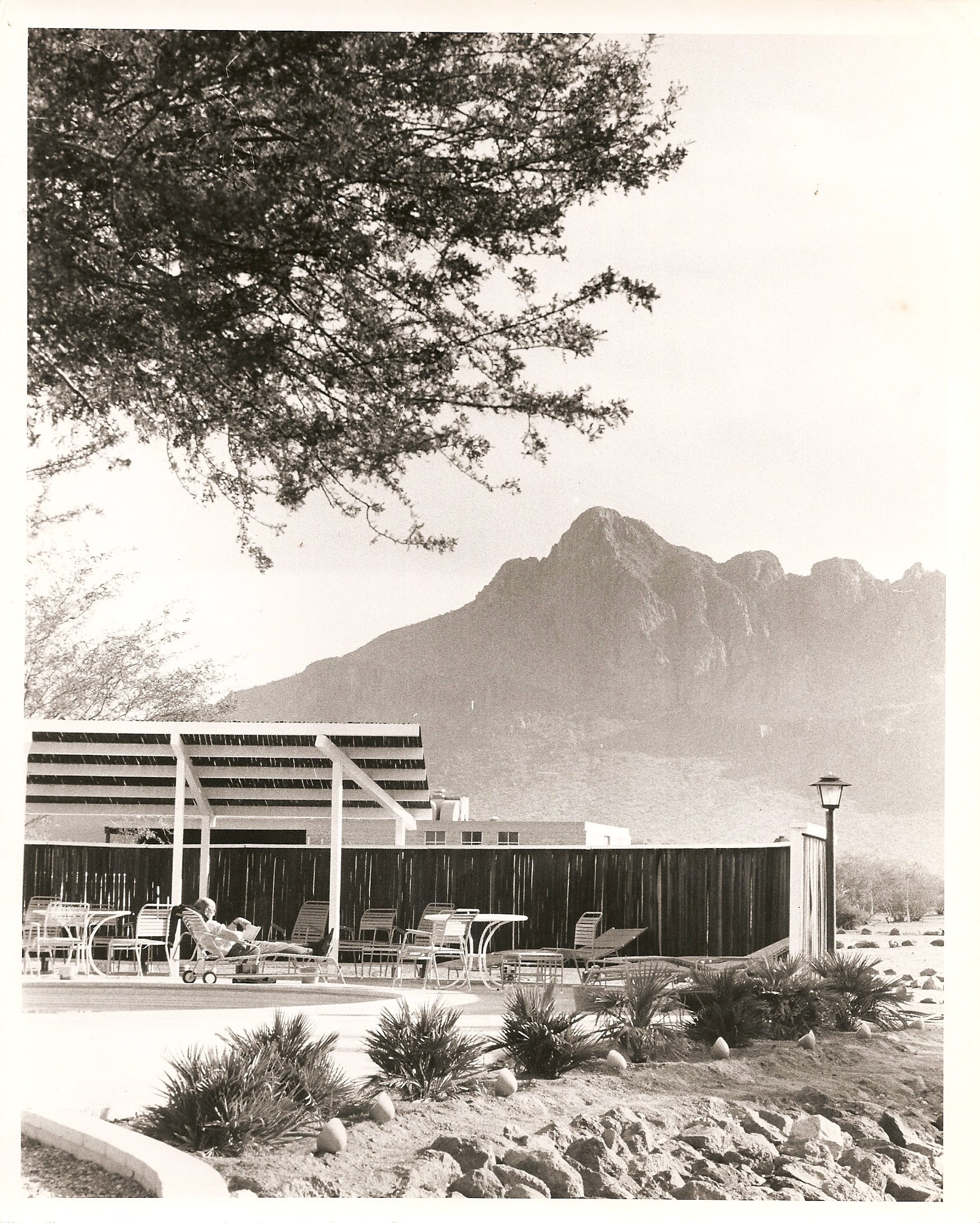 a black and white photo of a building with a mountain in the background