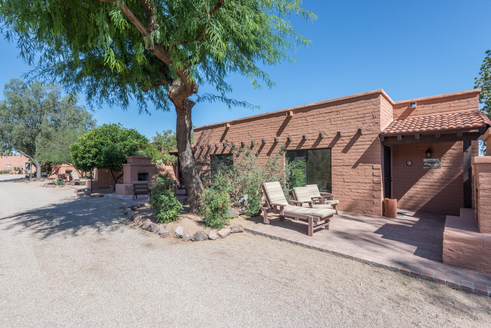 a brick building with chairs and a tree