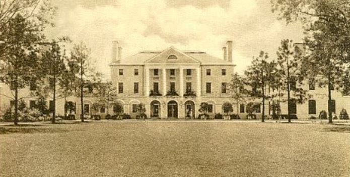 a large white building with trees in front