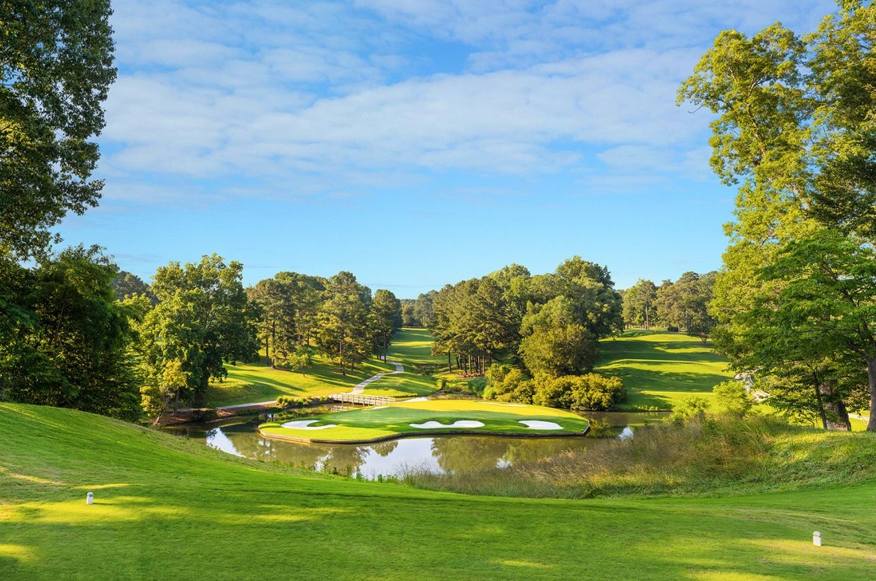 a golf course with a pond and trees
