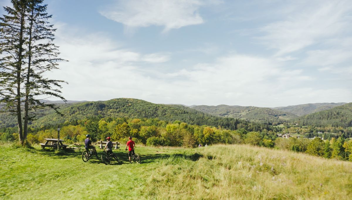 a group of people on bicycles in a grassy area with hills in the background