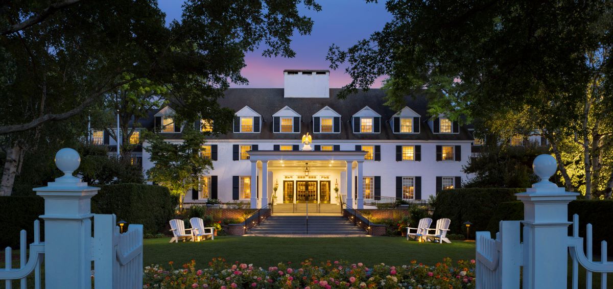 a large white building with a lawn and chairs in front of it