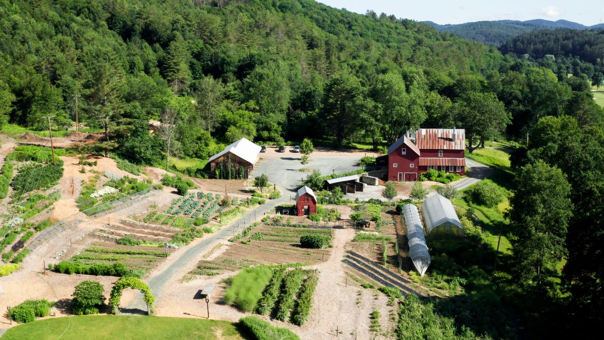 a farm with a red barn and a vegetable garden
