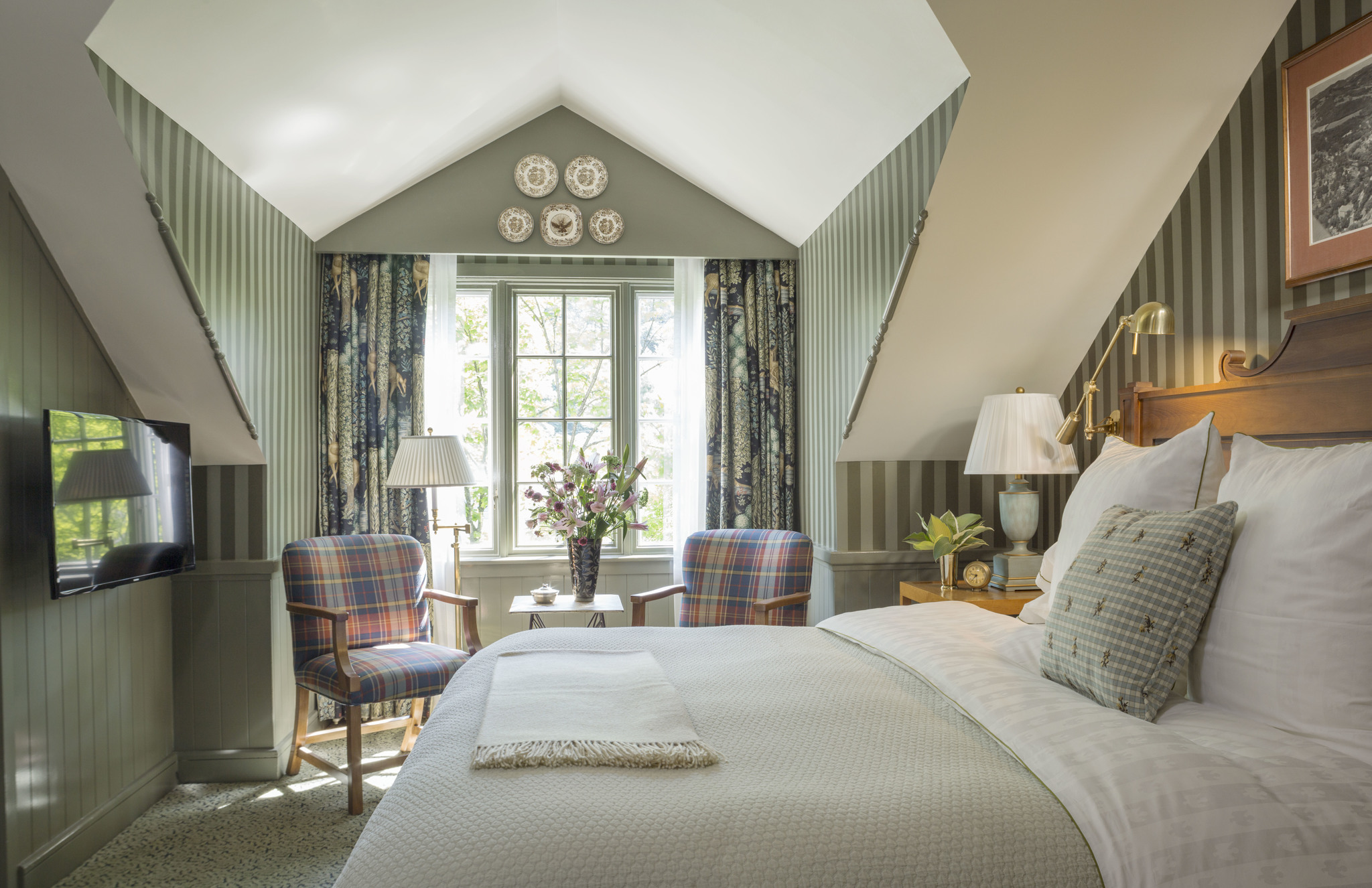a bedroom with striped walls and a bed and chairs