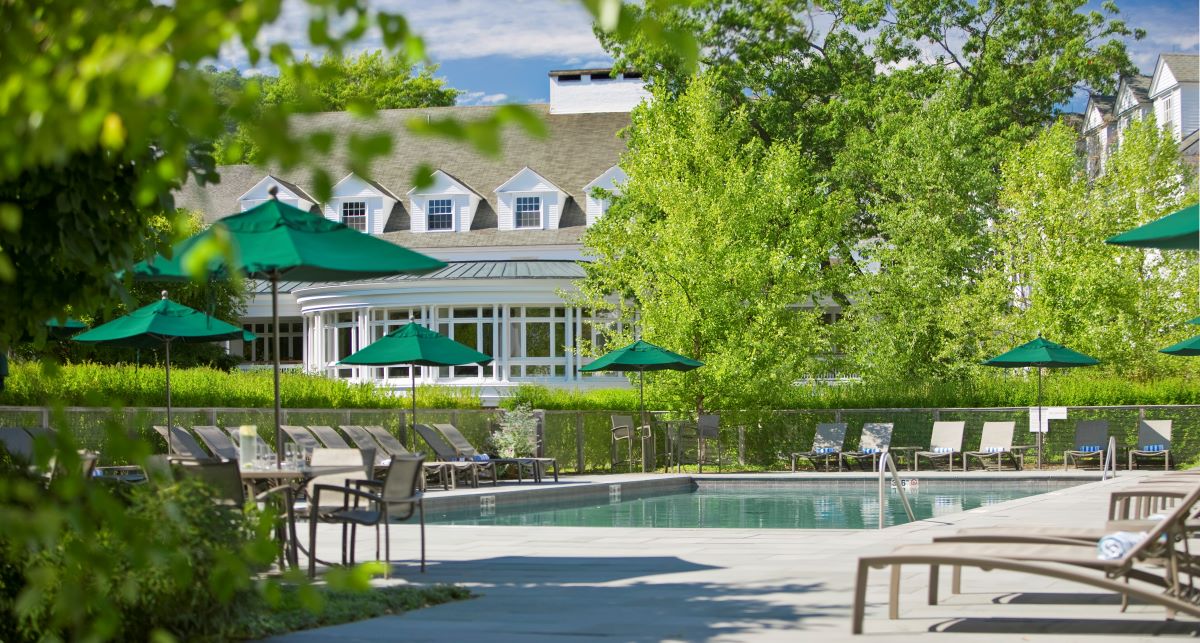 a pool with chairs and umbrellas by a building
