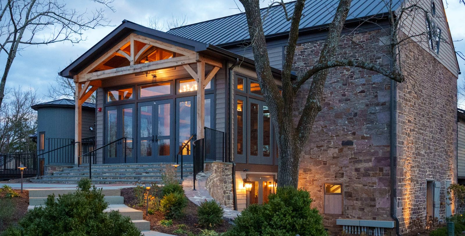 a building with a stone wall and a tree