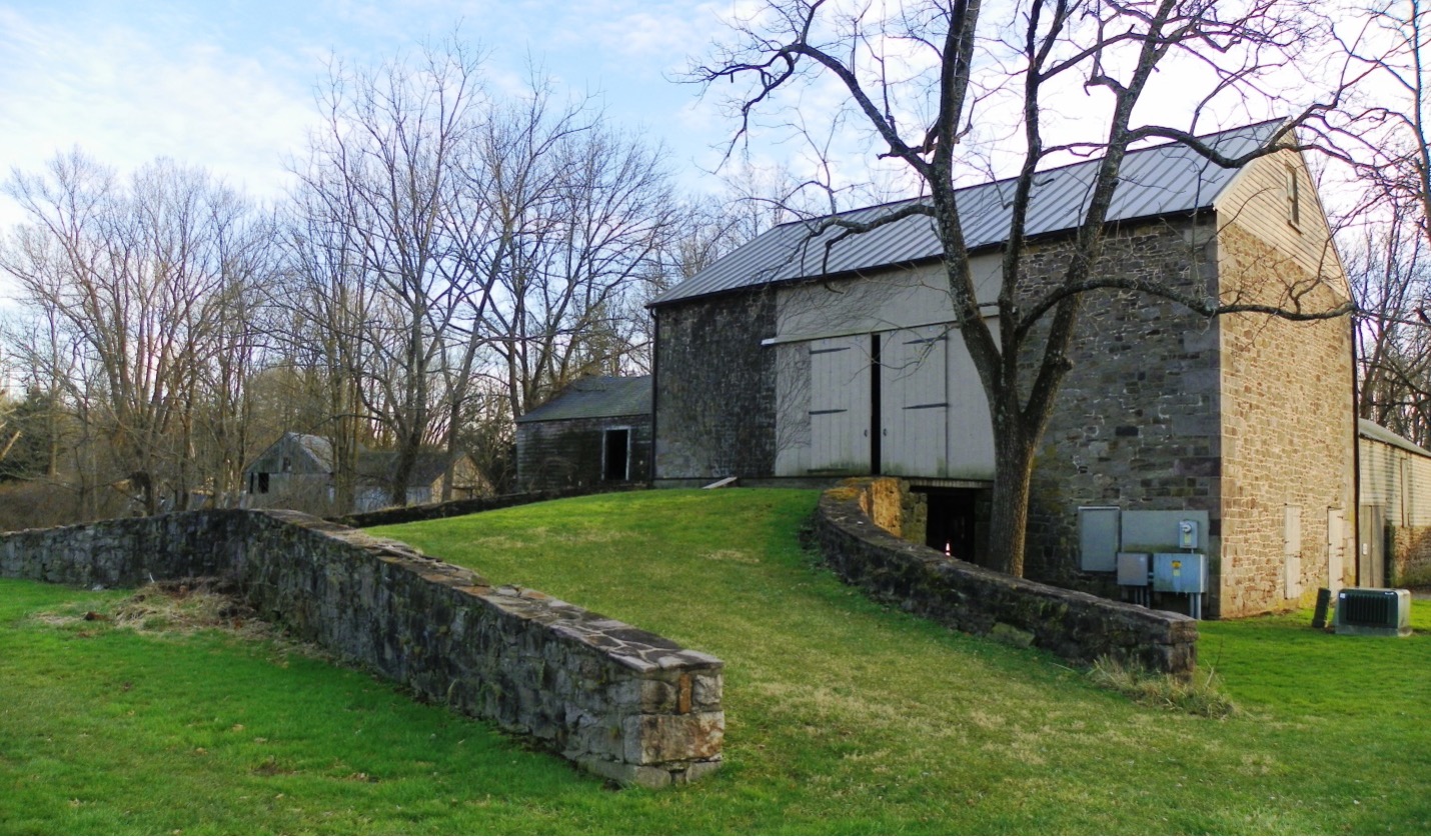 a stone building with a stone wall and grass