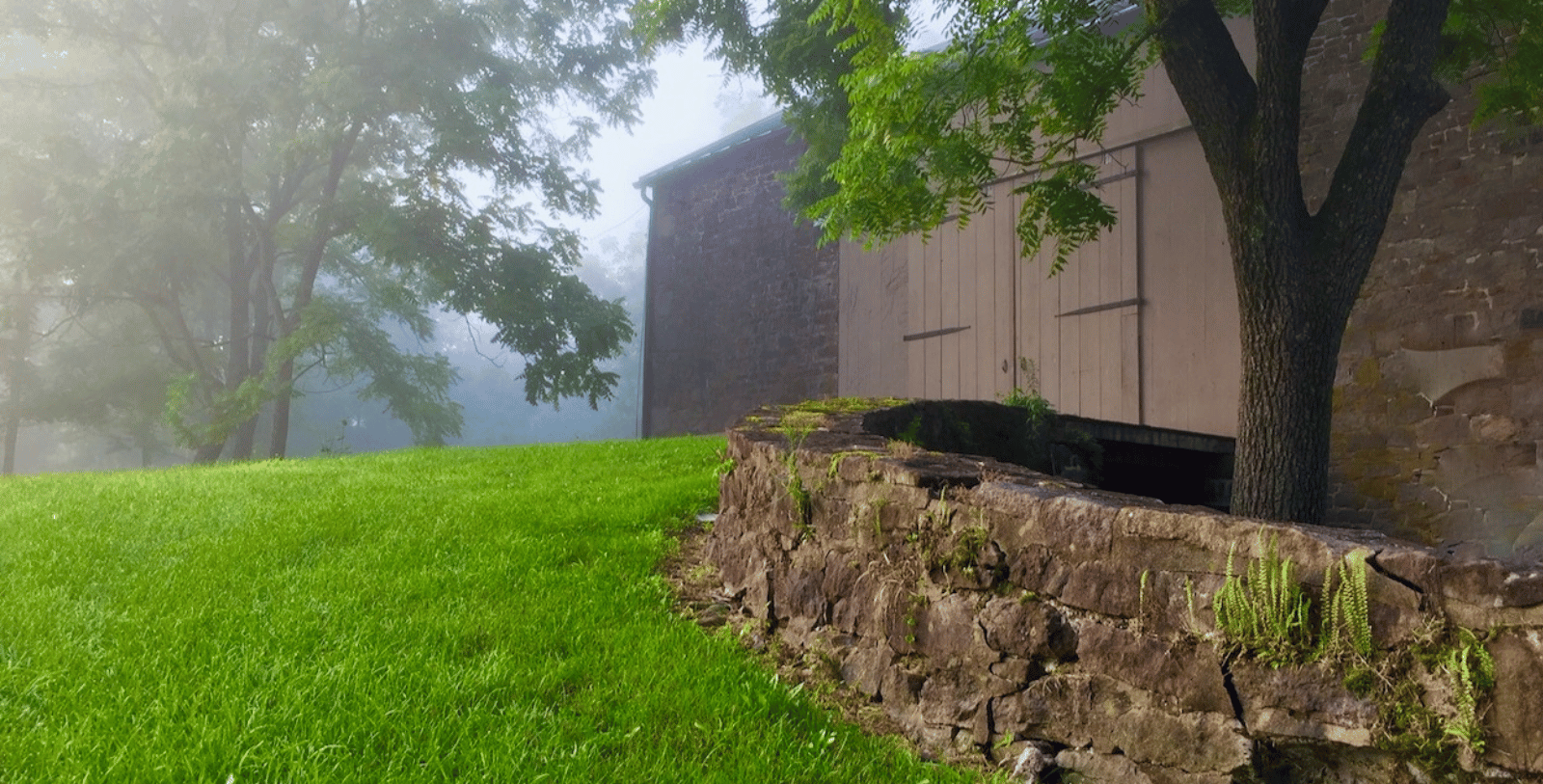 a stone wall and grass next to a building