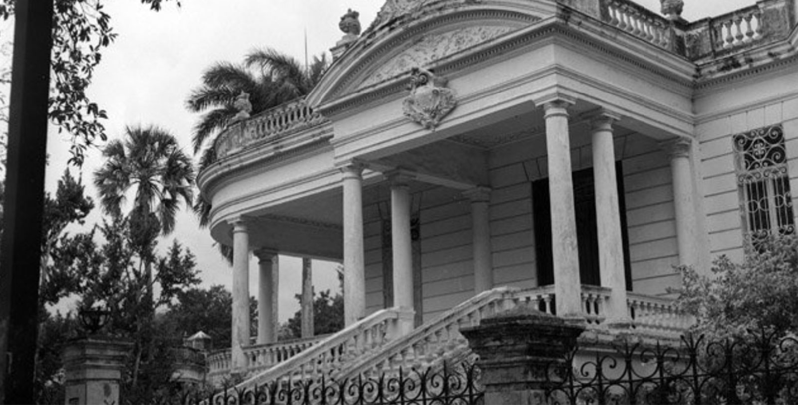 a white house with pillars and a fence