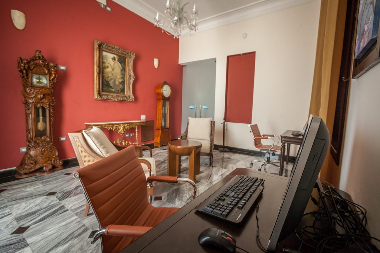 a desk with a computer and chairs in a room with red walls
