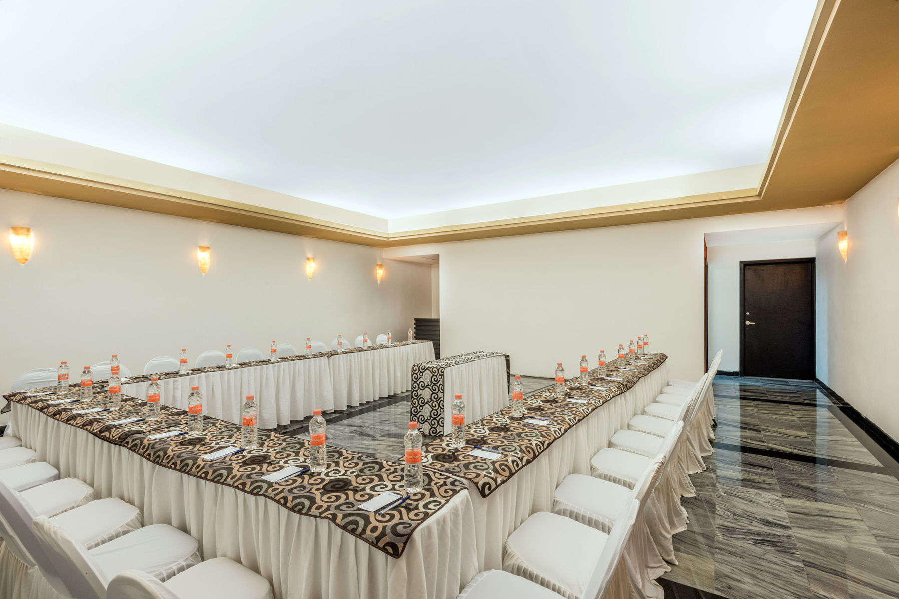 a long table with white chairs and a black and gold tablecloth